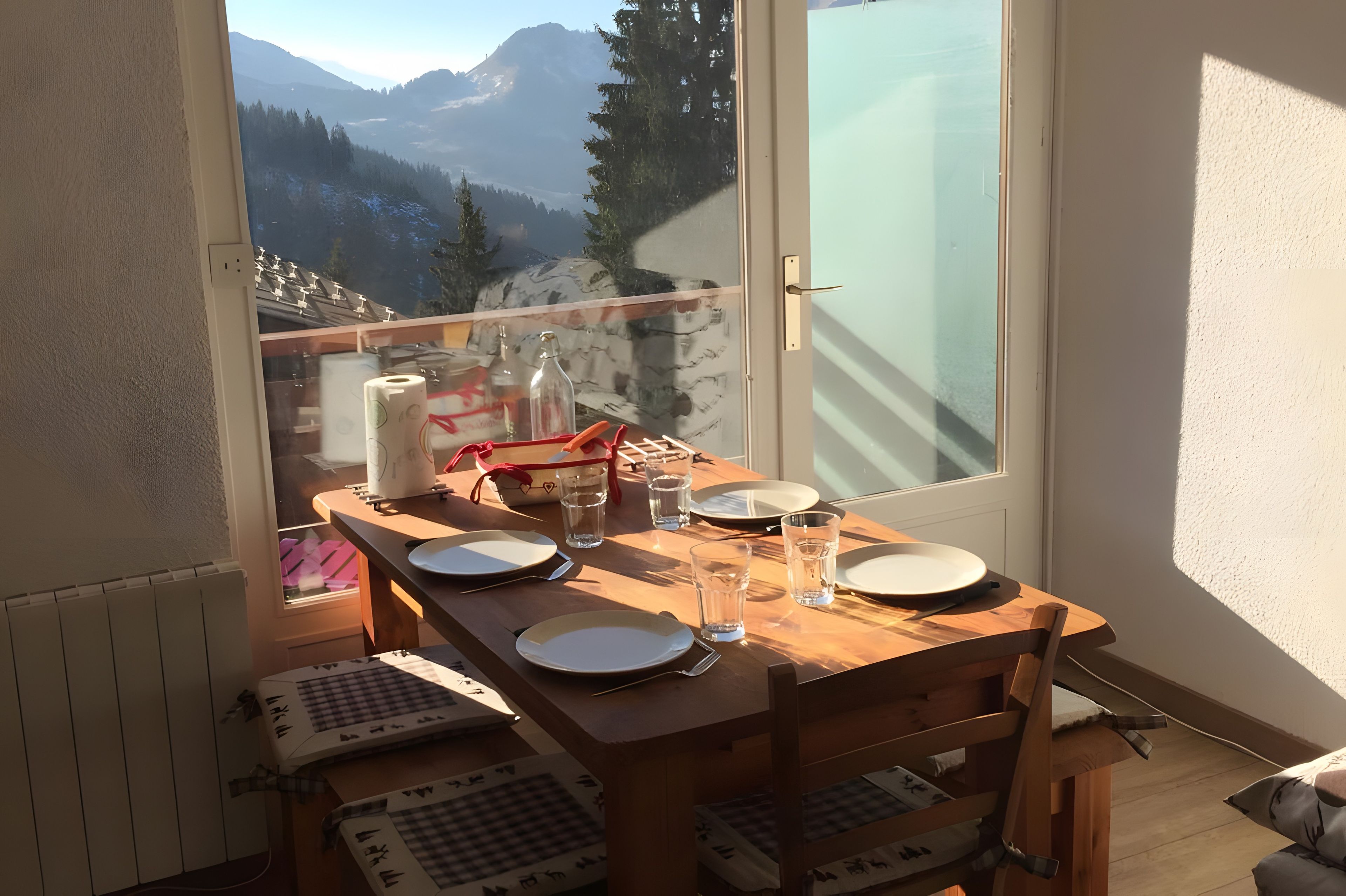 Ein Balkon mit Esstisch, mit Blick auf eine gebirgige Landschaft.