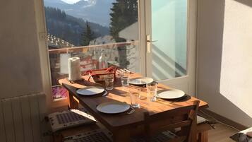 Ein Balkon mit Esstisch, mit Blick auf eine gebirgige Landschaft.