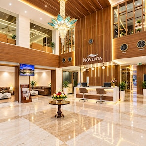 Un vestíbulo de hotel con mostrador de recepción, zona de estar y una lámpara de araña grande.