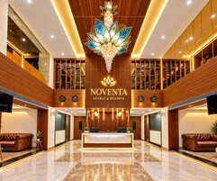 Un vestíbulo de hotel con una recepción, asientos cómodos y una lámpara decorativa.