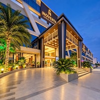 Entrada de hotel con diseño moderno, destacando un logotipo y una fachada bien iluminada.