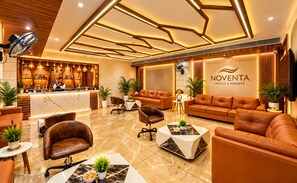 A hotel lobby with leather sofas, a reception desk, and a bar area.