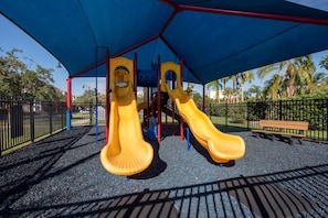 A playground with two yellow slides and a blue canopy. - Vista Cay 3BR Townhome- Near Universal (Orlando)