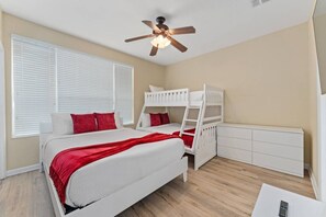A bedroom with a bunk bed, a single bed, a ceiling fan, and a white dresser. - Vista Cay 3BR Townhome w/ Resort Access (Orlando)