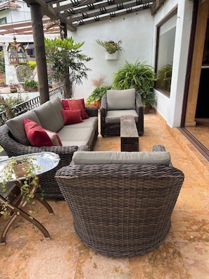 An outdoor seating area with wicker furniture, including a sofa and chairs, a small table, and a hanging planter. - Casa con alberca en Avandaro Valle de bravo (Valle de Bravo)