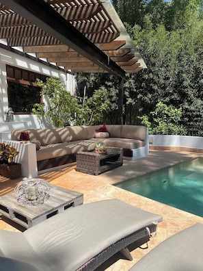 A poolside area with a lounge chair, a sofa, and a small table. - Casa con alberca en Avandaro Valle de bravo (Valle de Bravo)
