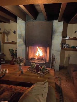 A cozy living room with a fireplace, a wooden table with a vase and candles, and a comfortable couch. - Casa con alberca en Avandaro Valle de bravo (Valle de Bravo)