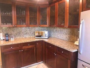 A kitchen with wooden cabinets, granite countertops, and a built-in microwave. - Casa con alberca en Avandaro Valle de bravo (Valle de Bravo)