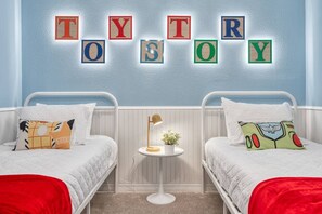A bedroom with two beds, a small round table with a lamp, and a wall with colorful letter blocks spelling "TYTROSOY". - 5BR Windsor Island Home w/ Private Pool (Davenport)