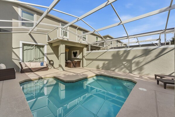 A modern outdoor swimming pool area with a glass ceiling, a lounge chair, and a sofa. - Luxury 4BR Townhome w/ Pool Champions Gate (Kissimmee)