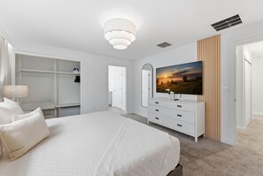 A bedroom with a bed, a dresser, a TV, a closet, and a door. - Luxury 4BR Townhome w/ Pool Champions Gate (Kissimmee)