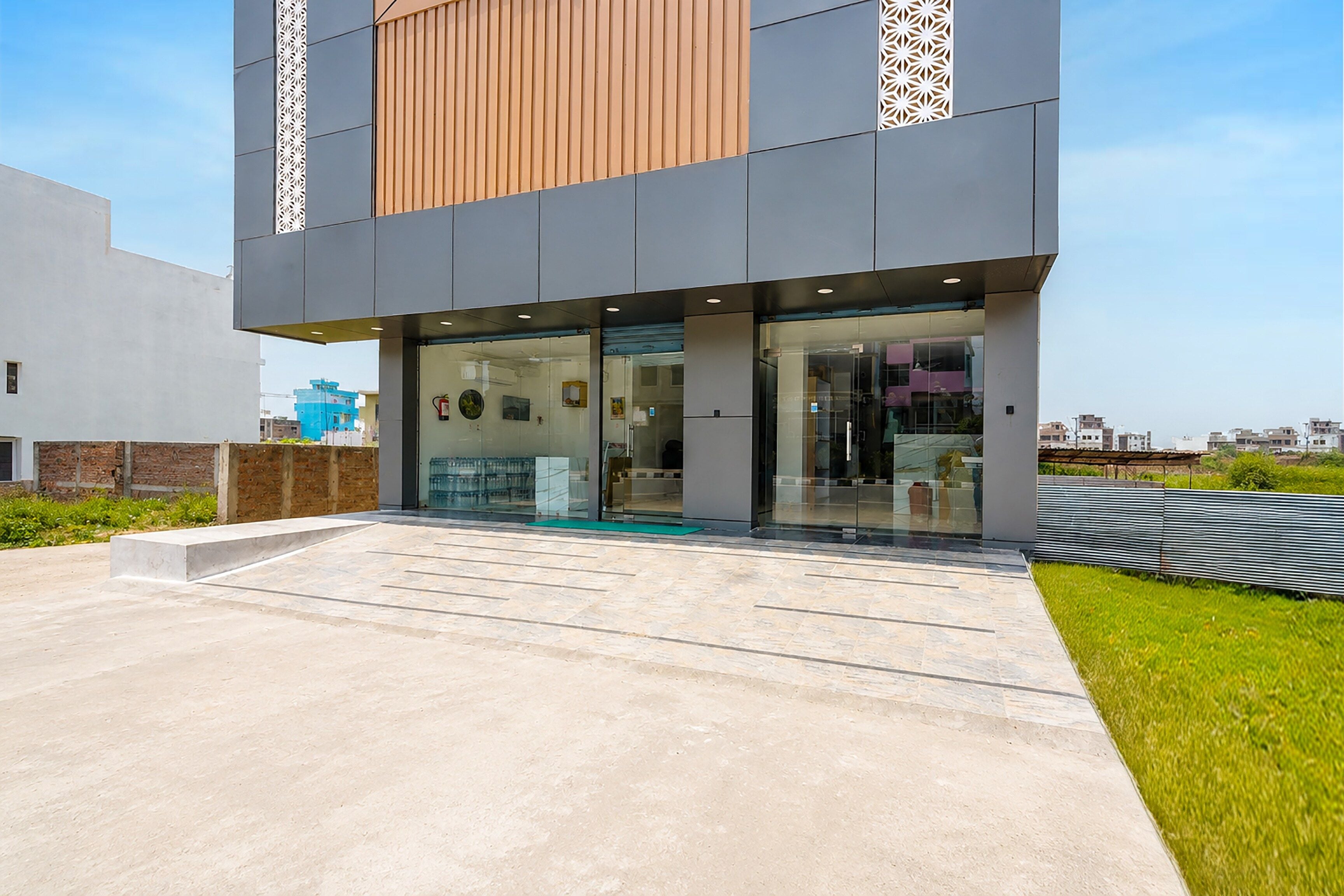 A modern building with a glass entrance, a concrete ramp, and a metal fence.
