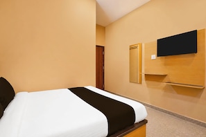 Habitació d'hotel amb un llit, una televisió penjada a la paret i una porta de fusta.