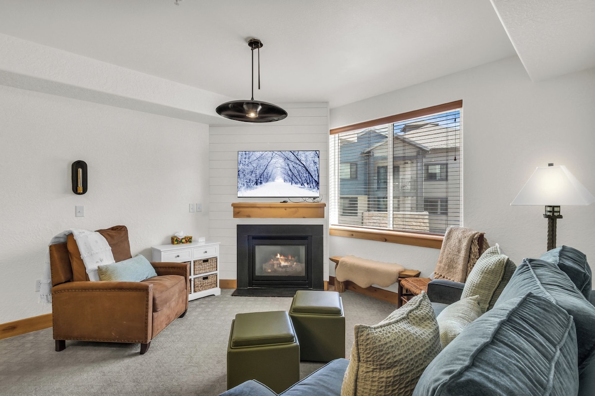 A cozy living room with a fireplace, a sofa, a coffee table, and a television.