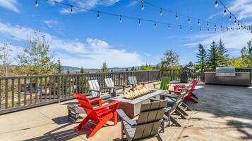 An outdoor patio with a fire pit, seating, and string lights.