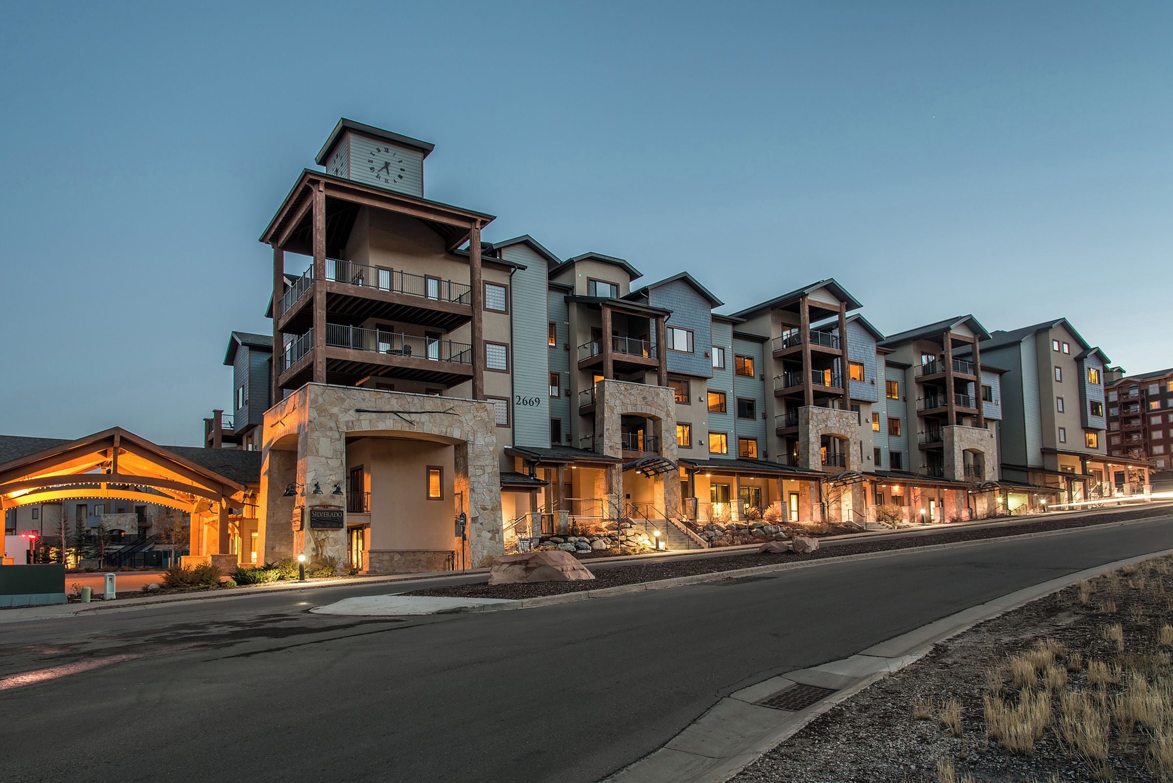 A multi-story hotel with balconies, a stone facade, and a well-lit entrance.