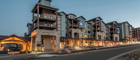 A multi-story hotel with balconies, a stone facade, and a well-lit entrance.