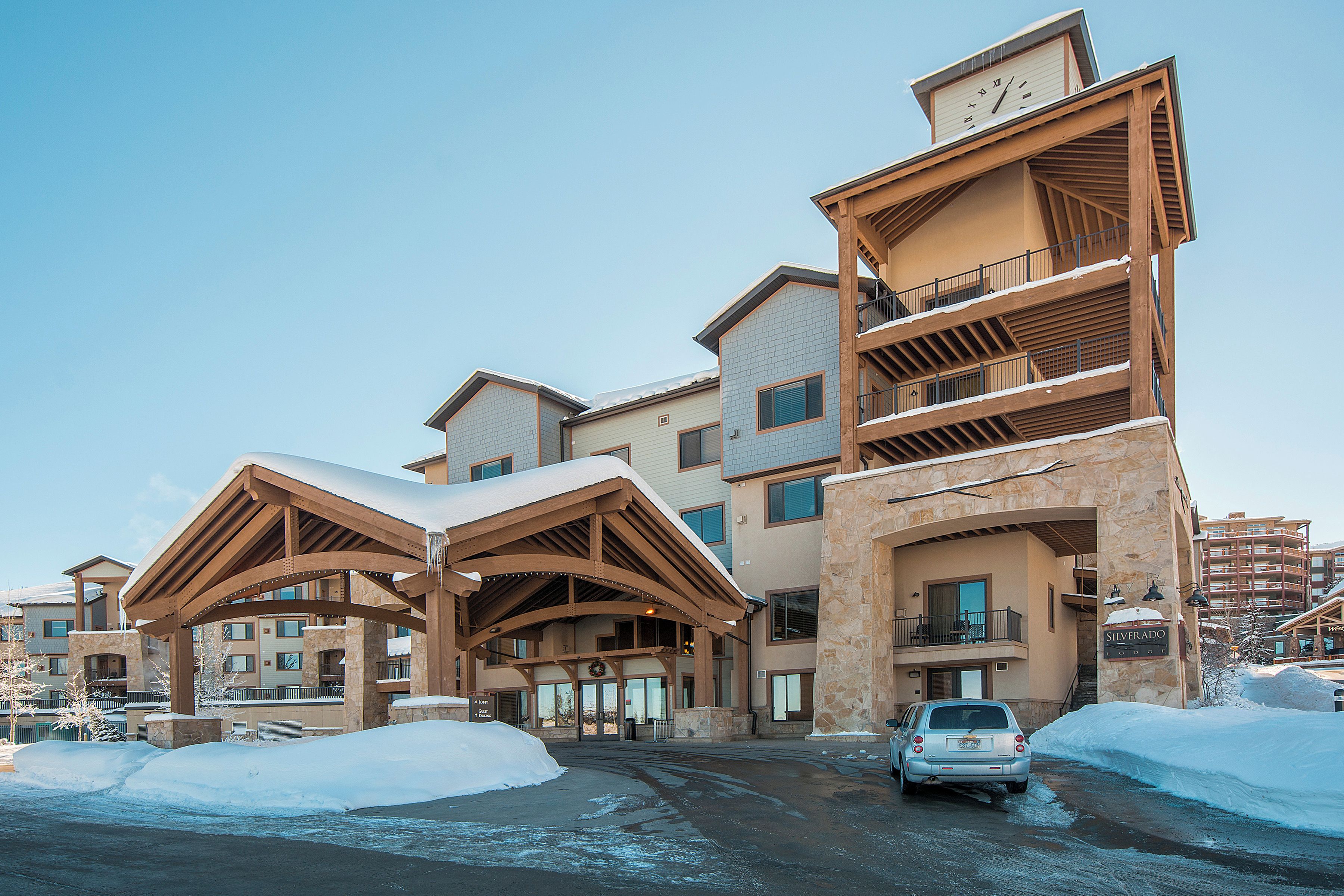 A multi-story hotel with a stone facade, wooden balconies, and a snow-covered entrance.