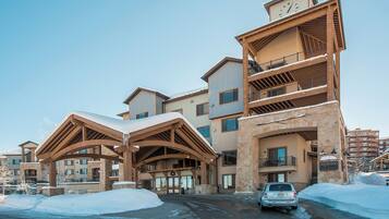 A multi-story hotel with a stone facade, wooden balconies, and a snow-covered entrance.