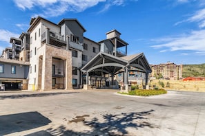 A multi-story hotel with a stone facade, balconies, and a covered entrance area. - Silverado Lodge by All Seasons Resort Lodging (Park City)