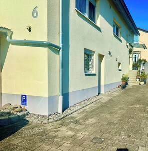 A building with a number '6' on the wall, a blue parking sign, and a paved street.