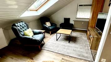 A loft-style room with a sloped ceiling, a large fur rug, a wooden coffee table, and a television.