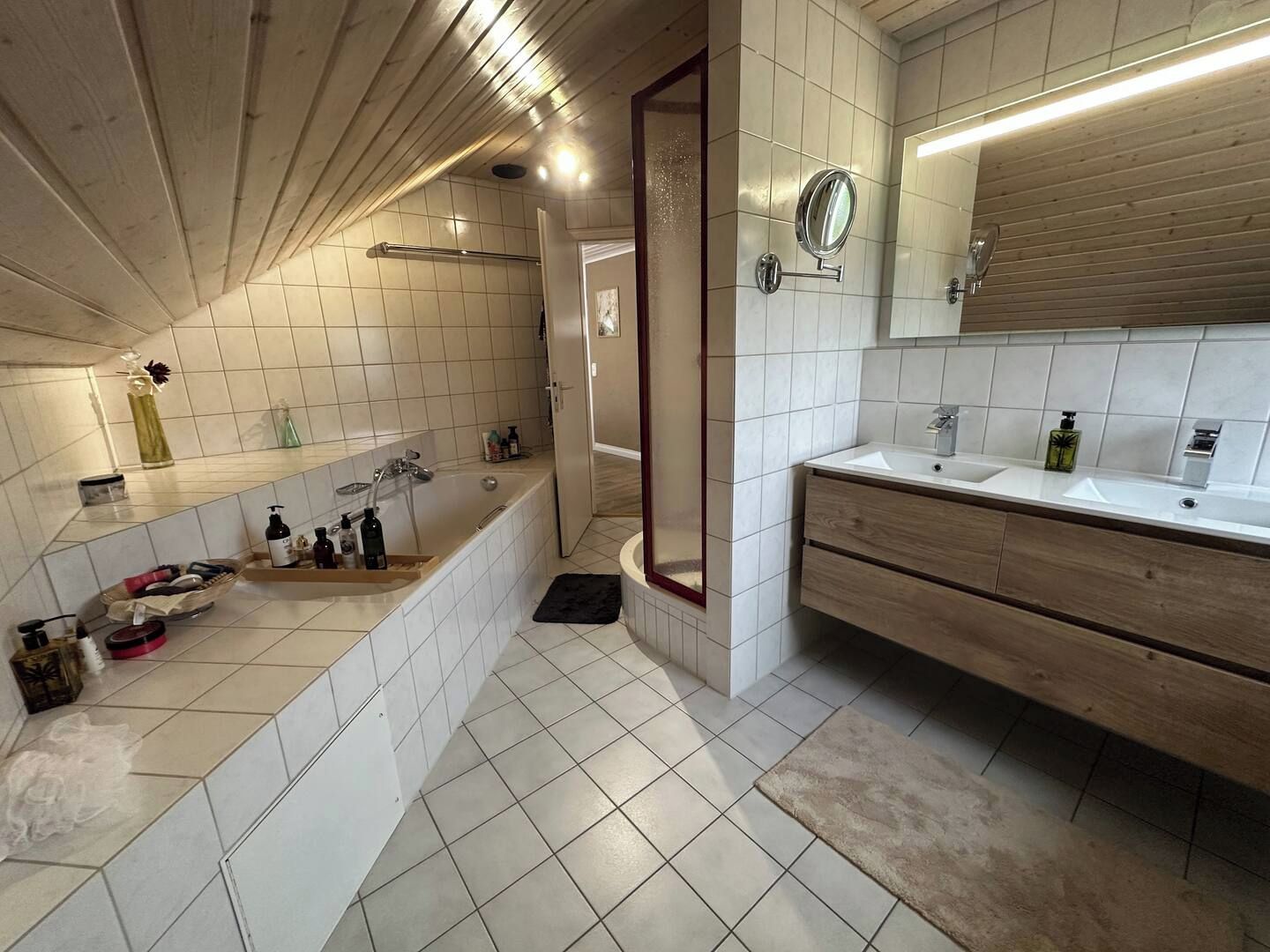 Ein modernes Badezimmer mit Badewanne, Waschtisch mit Spiegel und Duschbereich.