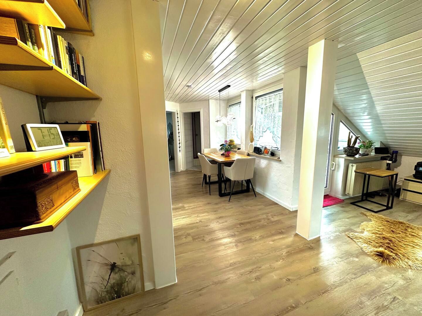 A modern interior with a dining area, bookshelves, and a staircase.