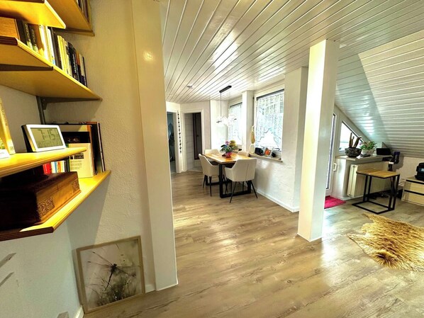 A modern interior with a dining area, bookshelves, and a staircase.