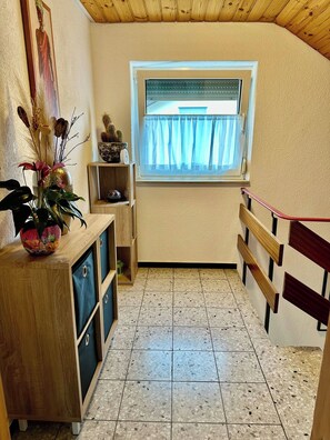 A small room with a window, a wooden cabinet, and a tiled floor.
