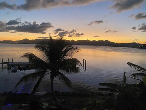 A sunset view over a calm body of water with a dock and palm trees. - New Listing (SAINT MARTIN)