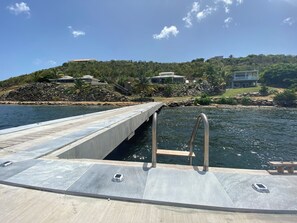 Eine Betonsteg, der sich in ein Gewässer erstreckt, mit blauem Himmel darüber.