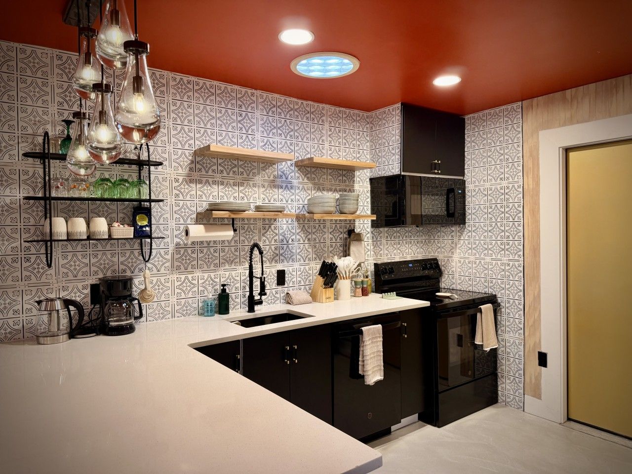 Una cucina moderna con isola centrale, mobili neri e schienale decorato.