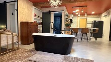 Une salle de bain moderne avec une baignoire sur pieds, un meuble en bois et un tapis à motifs.