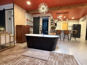 A modern bathroom with a freestanding bathtub, a wooden cabinet, and a patterned rug.