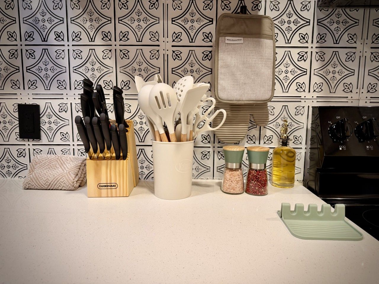 Un piano di lavoro da cucina con un portacoltelli, un contenitore per utensili, dosasali e un tagliere.