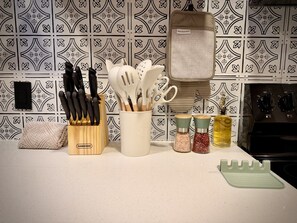 Un piano di lavoro da cucina con un portacoltelli, un contenitore per utensili, dosasali e un tagliere.