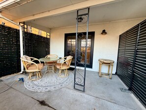 Une terrasse avec des meubles d’extérieur, une échelle en métal et un portail noir.