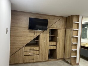 Une chambre à coucher moderne dotée d’un téléviseur encastré, d’une armoire en bois et d’une étagère en forme d’échelle.