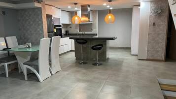 A modern kitchen with a central island, bar stools, and pendant lighting.