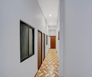 A hallway with a patterned floor, doors, and a ceiling light. - Classic Kali Ghat (Prayagraj)