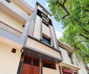 A hotel building with a prominent sign, multiple balconies, and a tree in the foreground. - Classic Kali Ghat (Prayagraj)