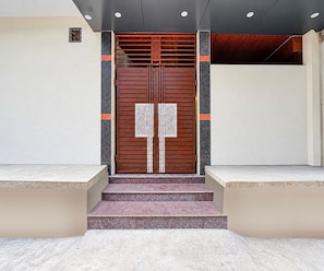 A modern entrance with a wooden double door, a small window, and a set of stairs leading up to the door. - Classic Kali Ghat (Prayagraj)