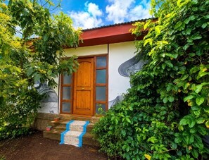 A house with a wooden door, a red roof, and a mural on the wall.