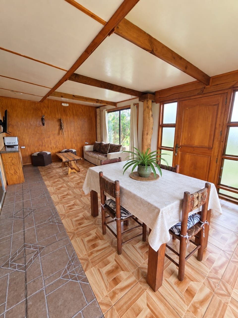 A dining area with a table set for four, wooden chairs, and a large window providing natural light.