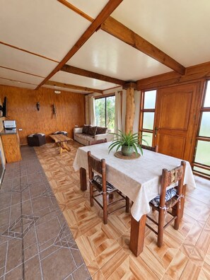 A dining area with a table set for four, wooden chairs, and a large window providing natural light.