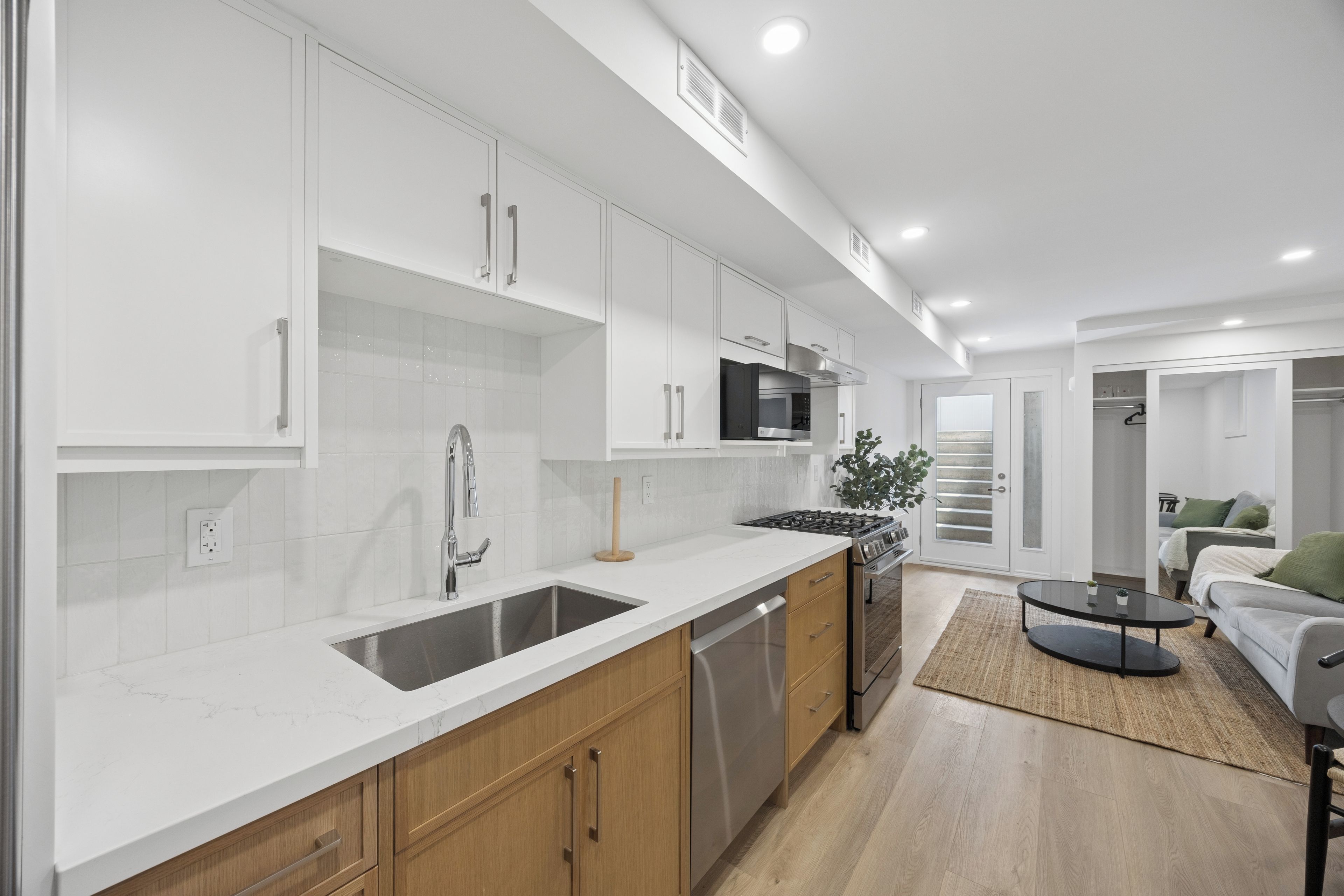 Una cocina moderna con armarios blancos, electrodomésticos de acero inoxidable y encimera de madera.
