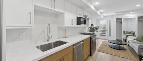 Una cocina moderna con armarios blancos, electrodomésticos de acero inoxidable y encimera de madera.