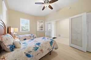 A bedroom with two beds, a ceiling fan, and a sliding door. - Spacious 3-bedroom family-friendly condo in Clearwater Beach (Clearwater)