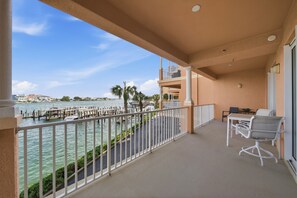 A balcony with a view of the water, a table with chairs, and a railing. - Spacious 3-bedroom family-friendly condo in Clearwater Beach (Clearwater)